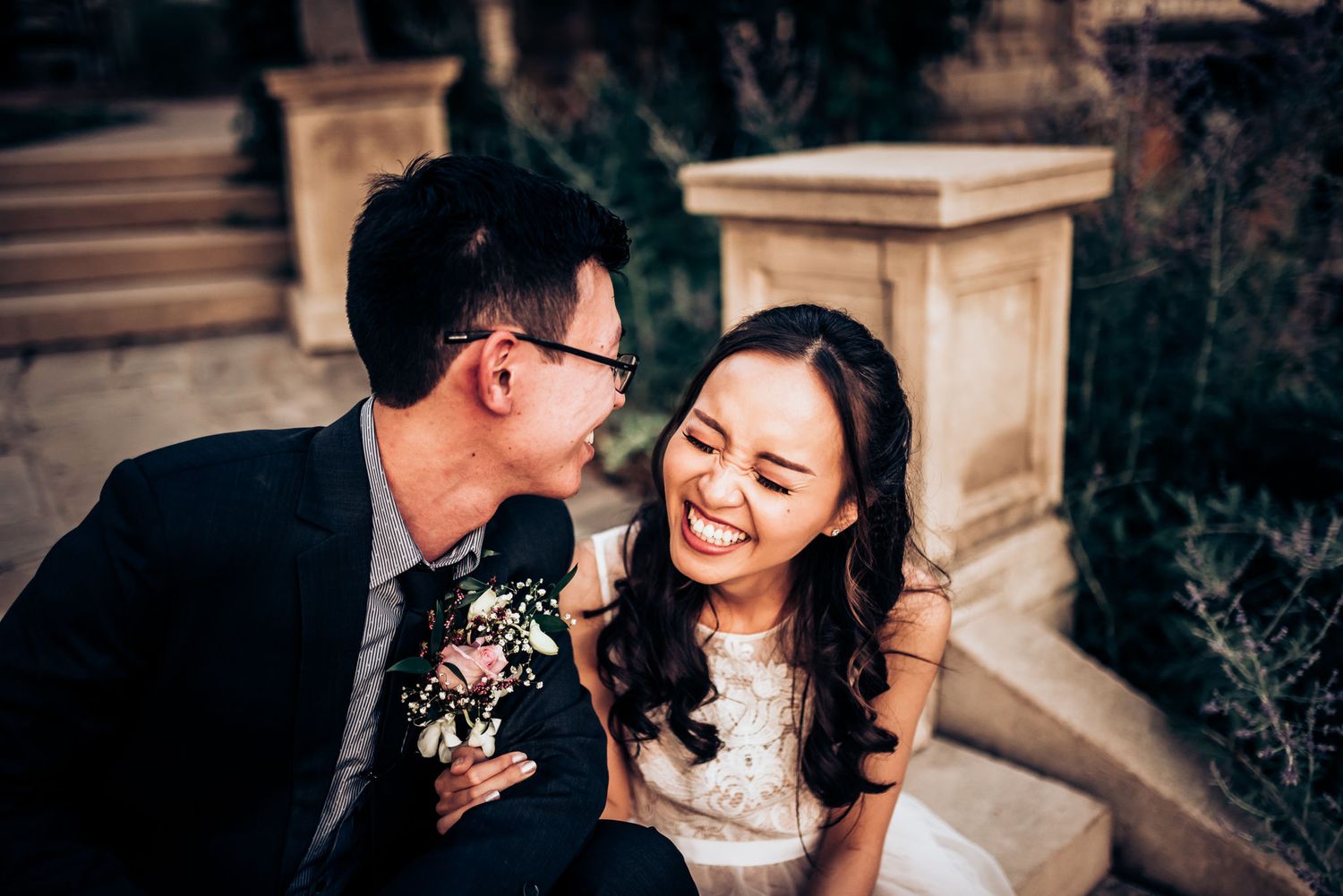Candid moment of wedding couple laughing together on ornate stone steps.
