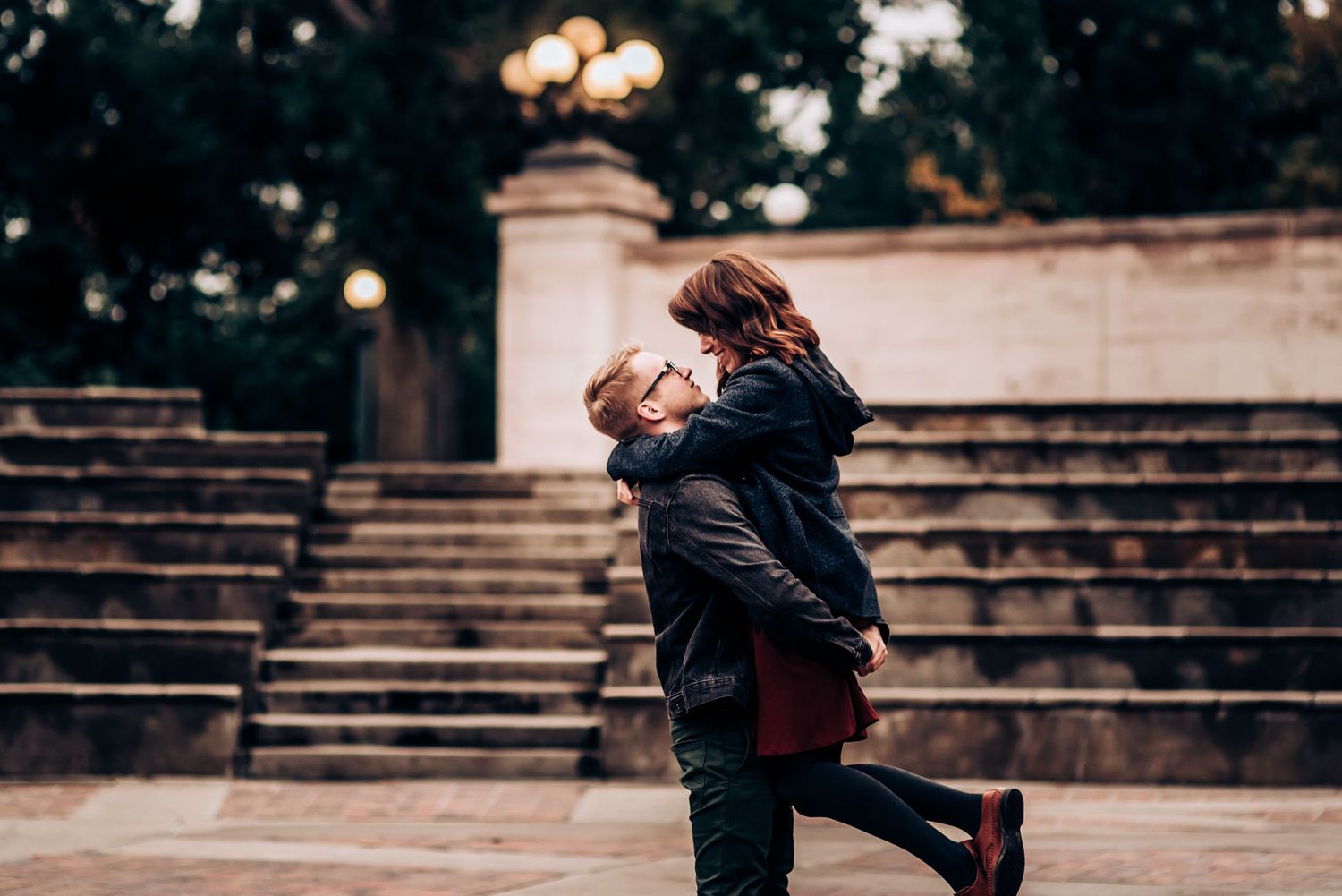A joyful couple embraces and spins on stone steps during their romantic photoshoot.