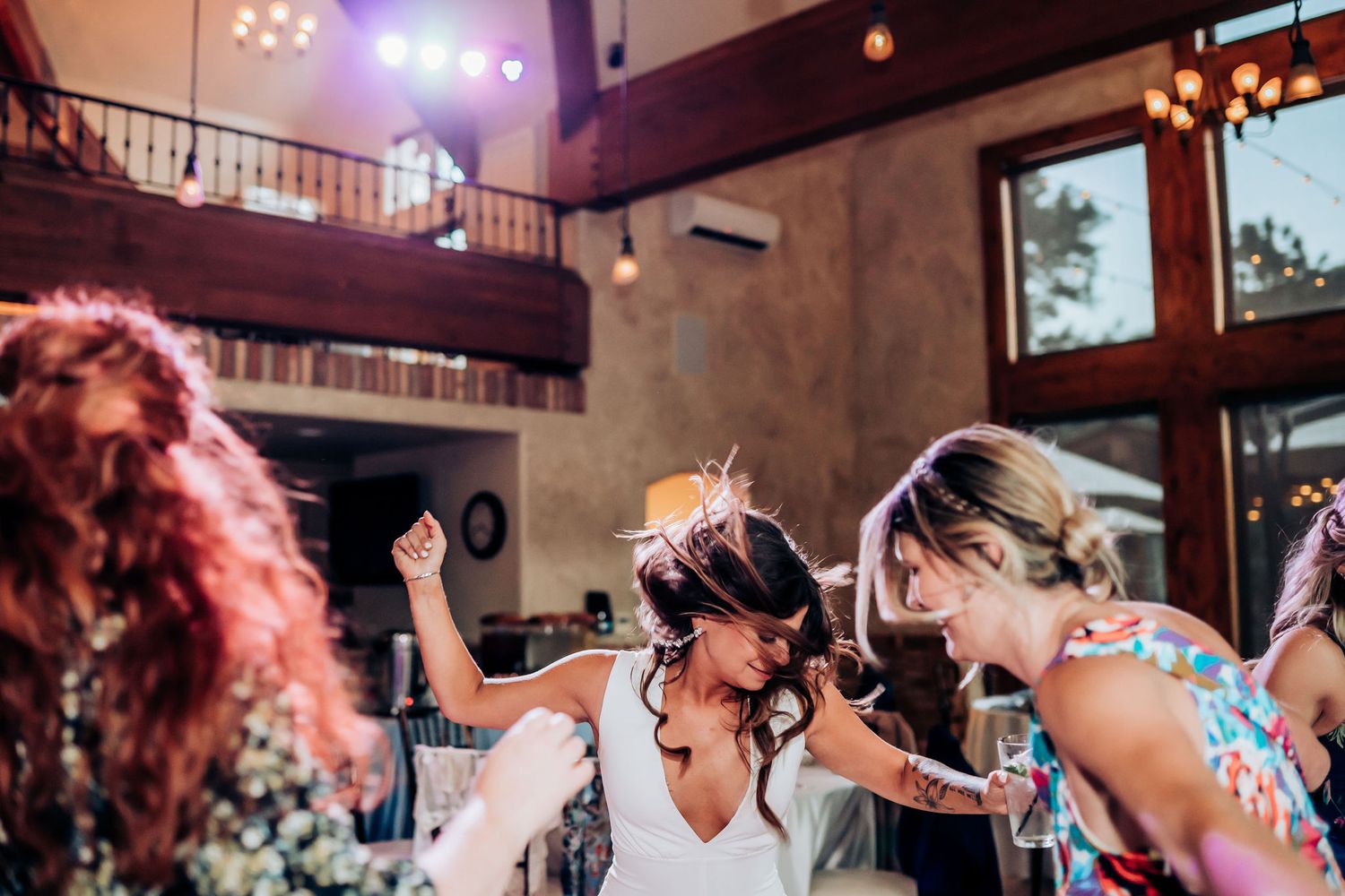 Energetic wedding reception dancing captured under dramatic lighting in a rustic venue.