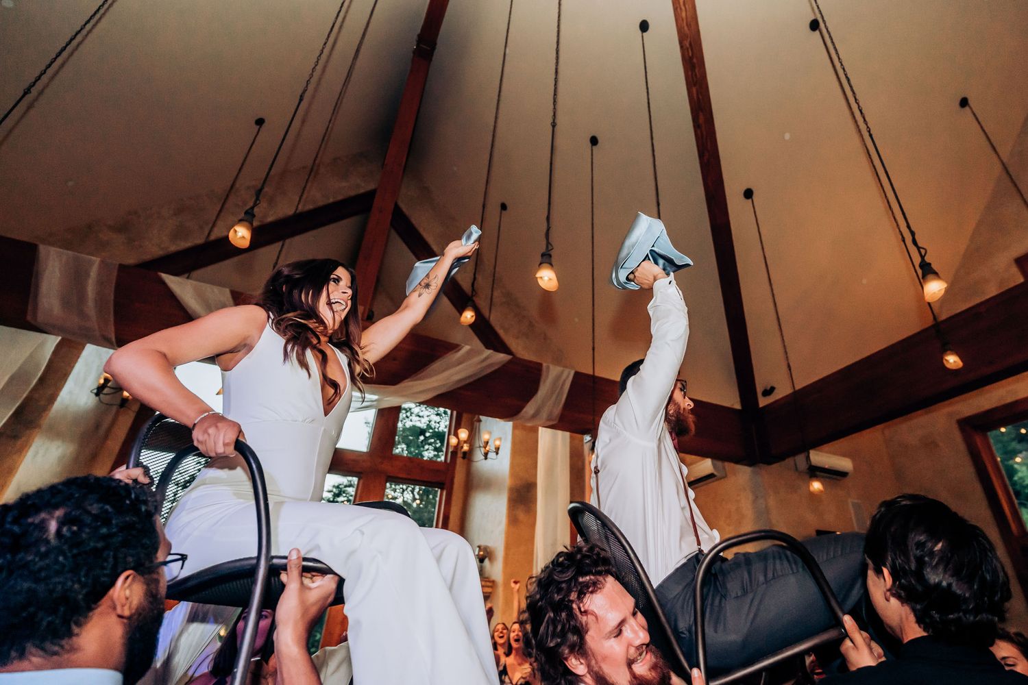 Wedding celebration with guests lifting someone high in the air during a traditional dance.