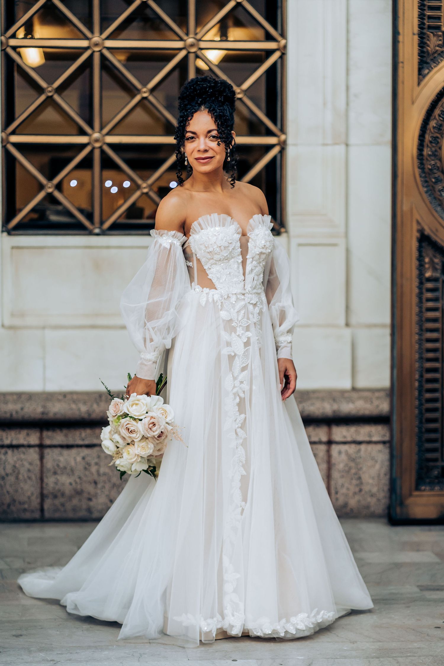 A wedding dress featuring delicate lace details, balloon sleeves, and a flowing tulle skirt.