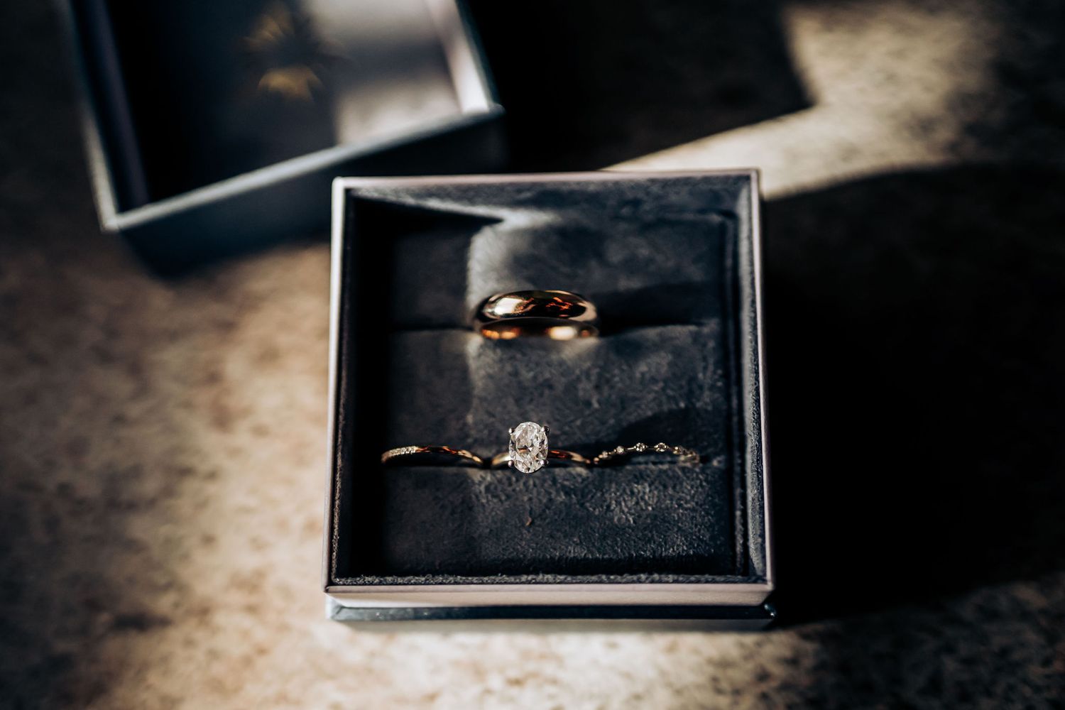 Wedding rings displayed in a black box with dramatic lighting.