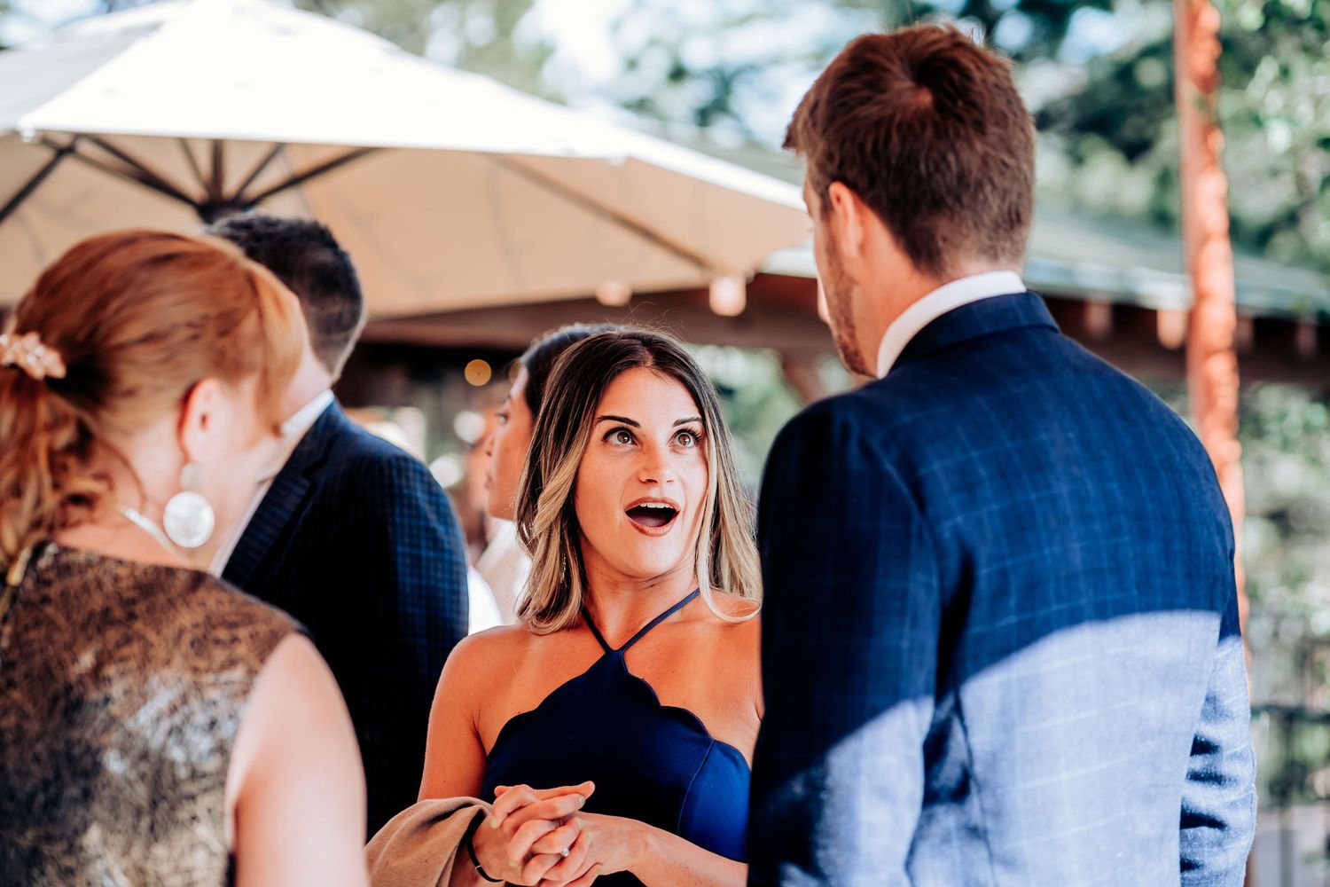 Candid moment of wedding guests sharing excited reactions during outdoor reception.