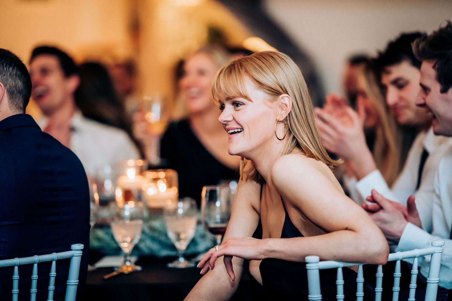 Guests share joyful reactions during an evening wedding reception celebration.