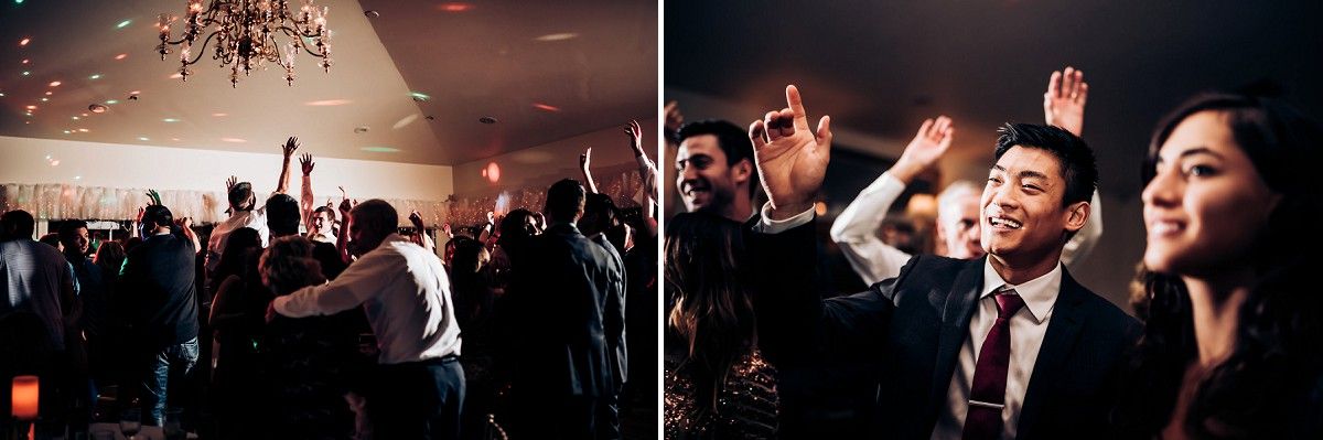 Silhouettes of party guests dancing with raised hands under chandeliers at a celebration.