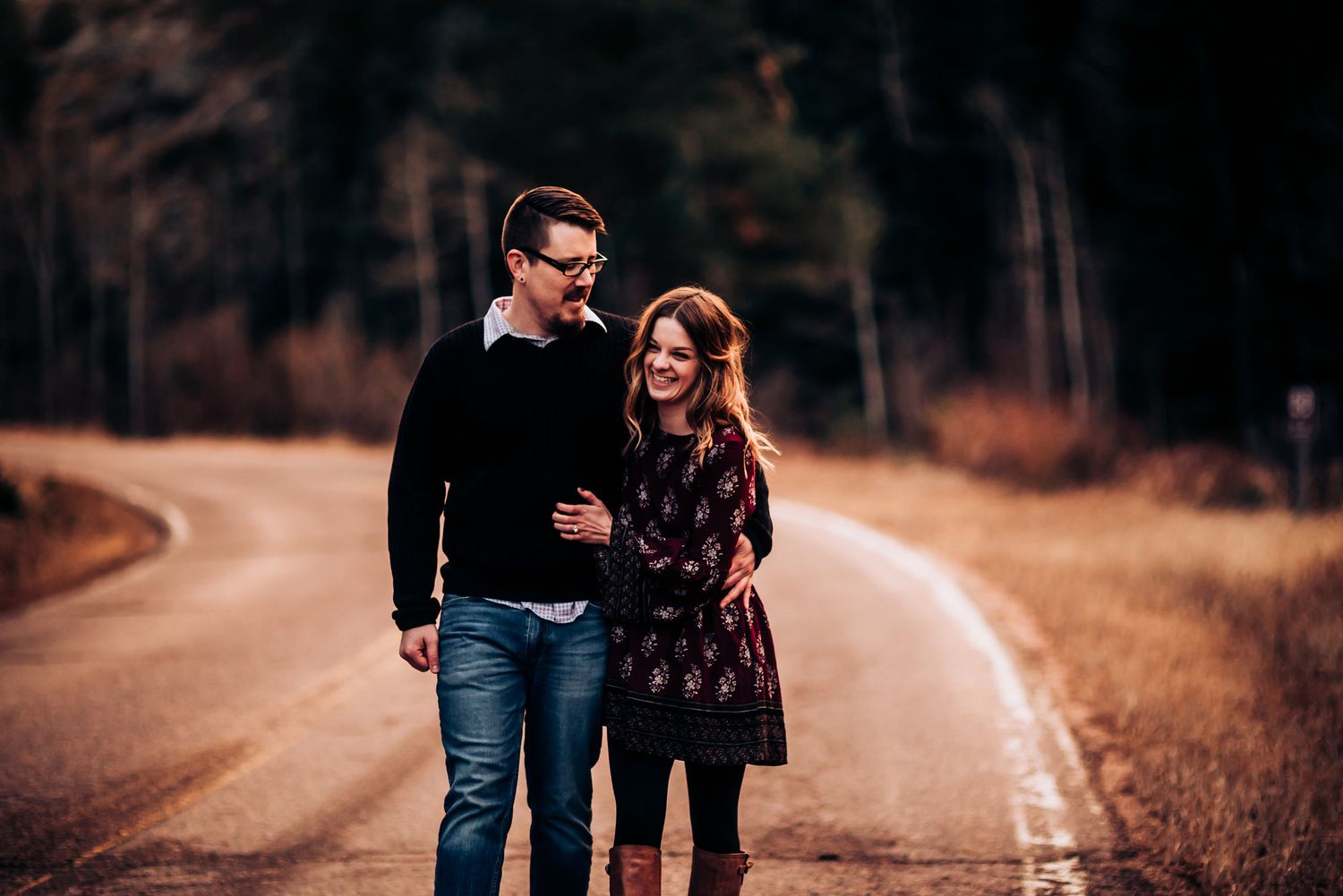 Couple walking together on a winding country road during golden hour.