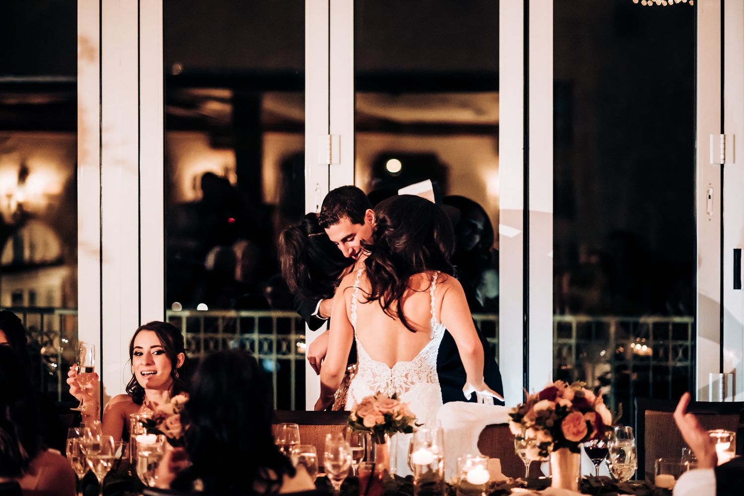 Reception guests enjoy a lively celebration at an elegant candlelit dinner table.