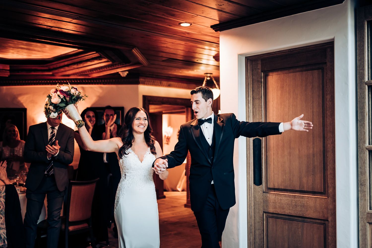 Joyful celebration moment in an elegant venue with wooden ceiling and warm lighting.