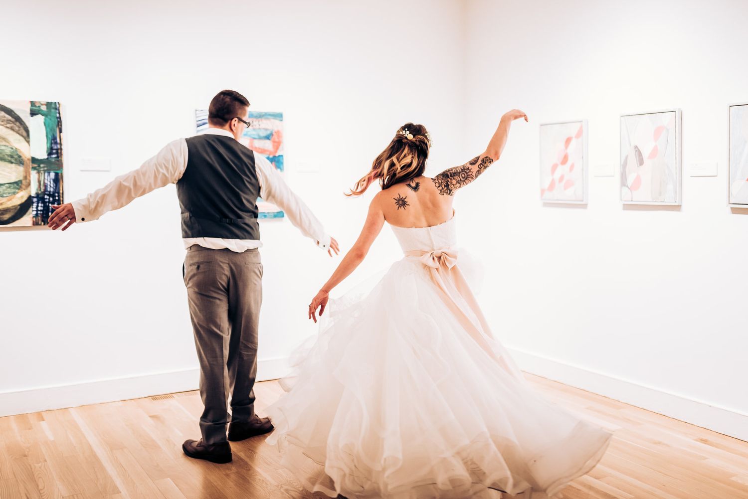 A couple dances playfully in an art gallery surrounded by modern artwork.