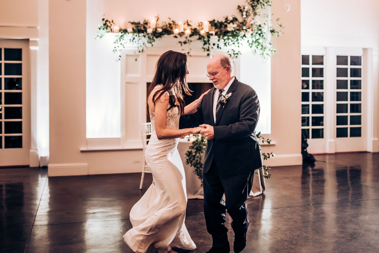 A romantic dance in an elegant ballroom under a floral arch.
