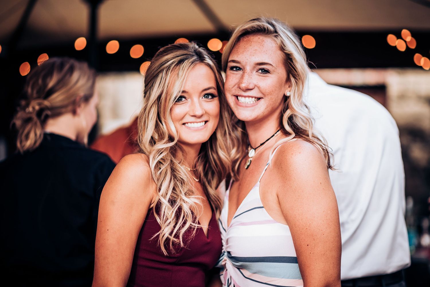 Two smiling guests in formal attire enjoying themselves at a wedding reception.