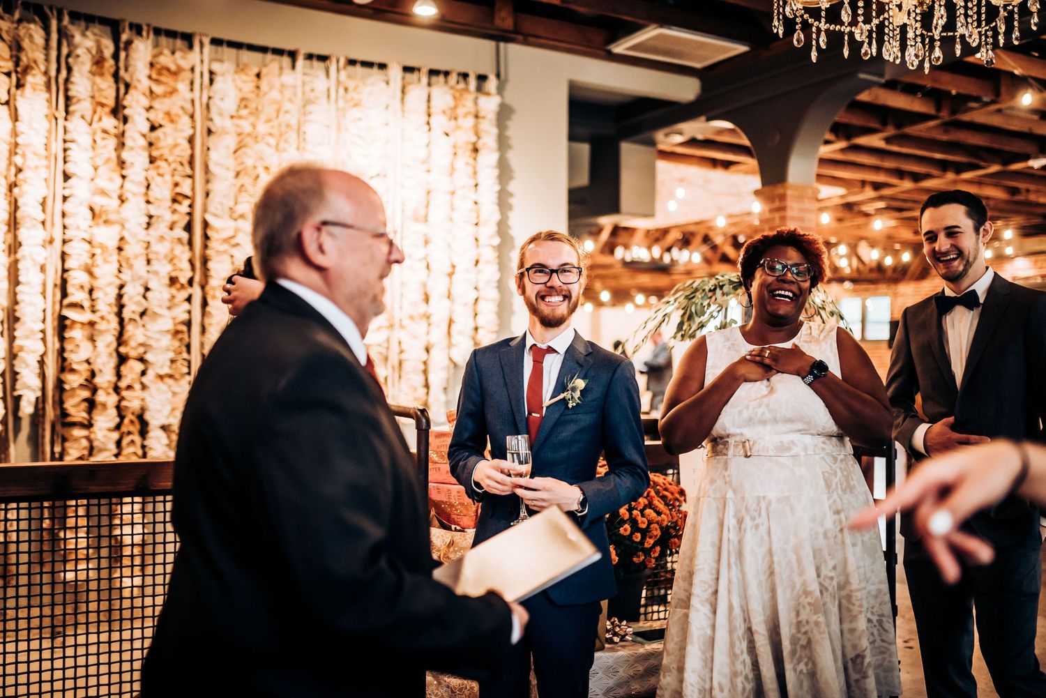 Wedding ceremony moment in an elegantly lit venue with decorative string lights and curtains.