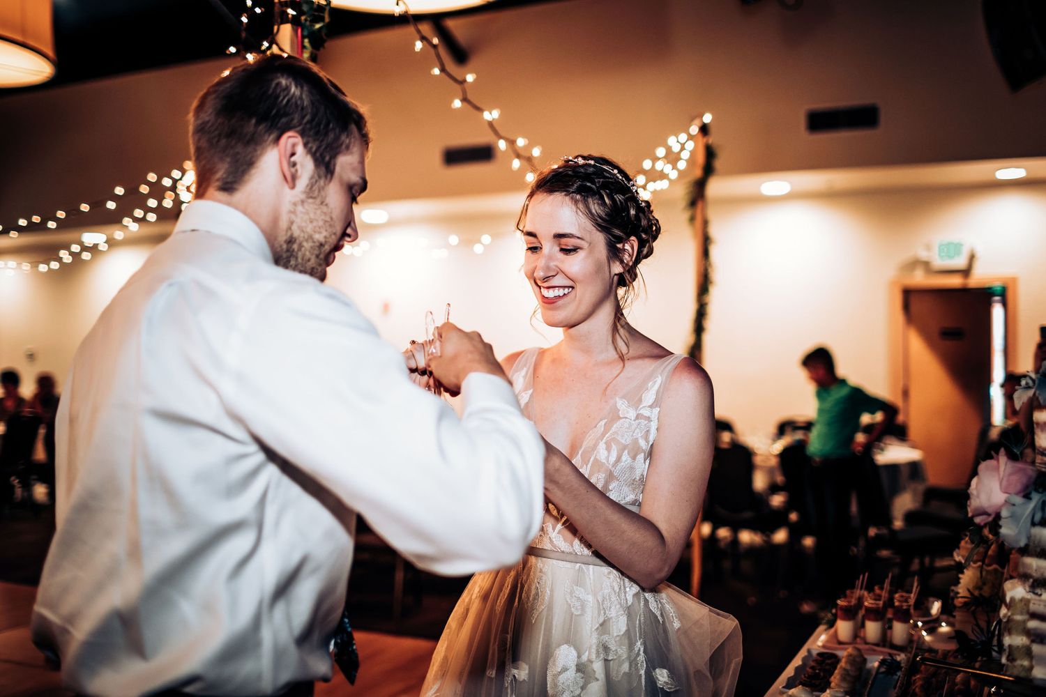 Couple sharing first dance at wedding reception under twinkle lights.