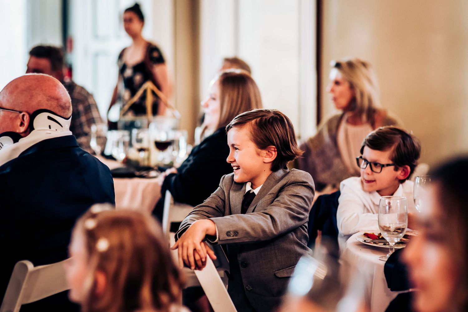 Young guests seated at formal dinner tables during reception celebration.