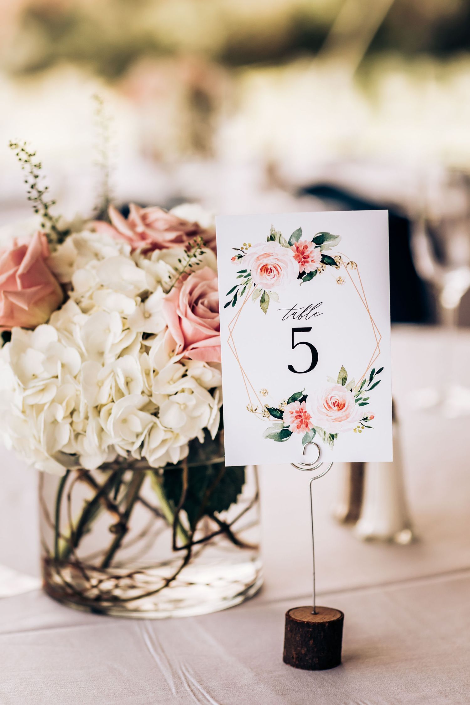 Romantic floral centerpiece with table number 5 card featuring watercolor roses and greenery.