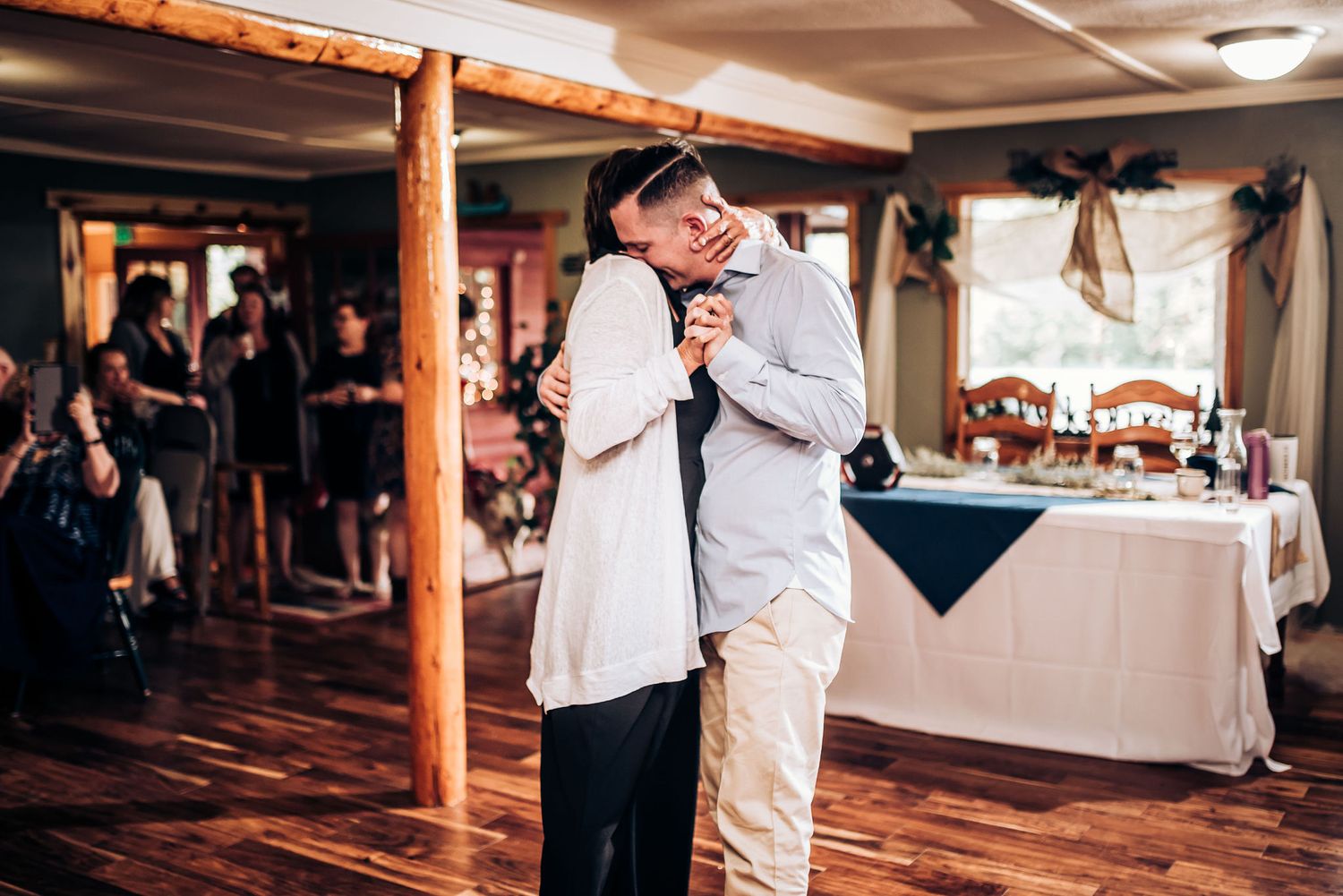 Two people share a tender moment while dancing together at an indoor reception.