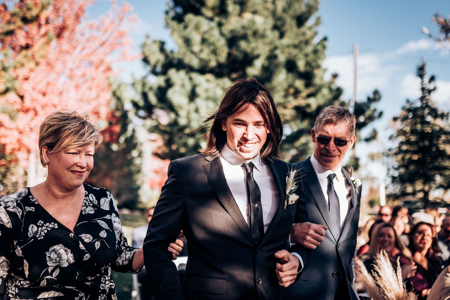 Wedding party members walking together and laughing during an outdoor ceremony.