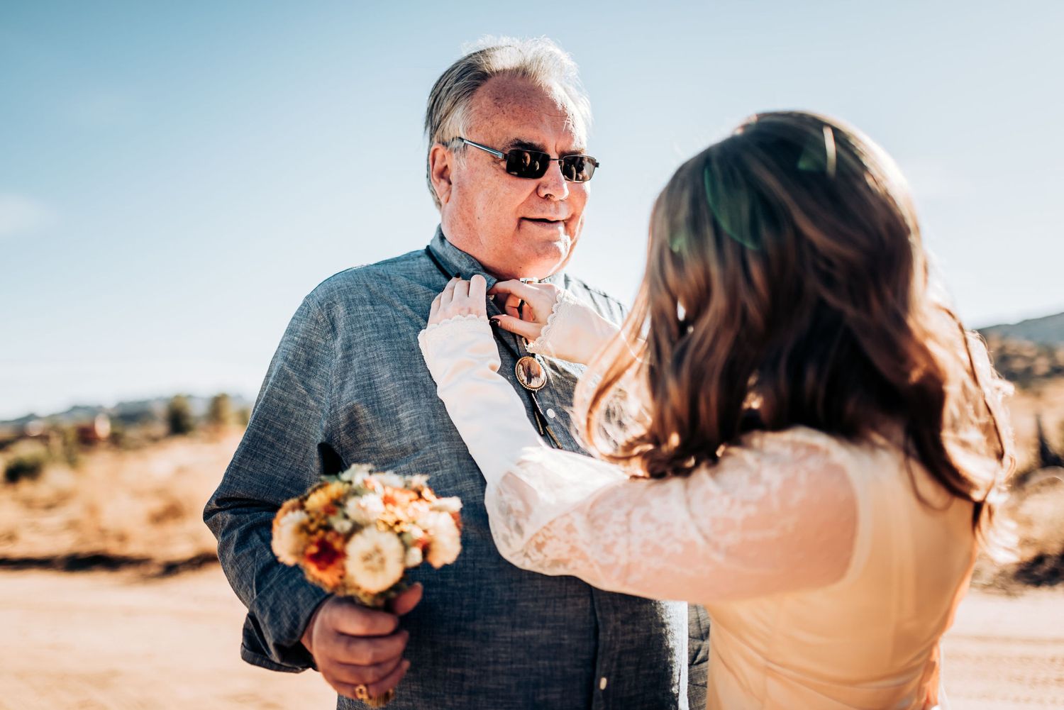 A touching moment during a desert wedding ceremony with Joshua trees in background.