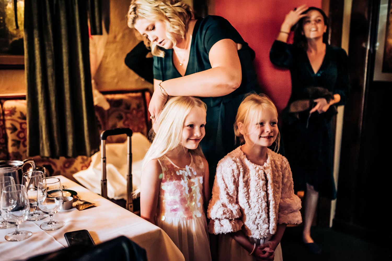 Children in party dresses smiling during a celebratory dinner.