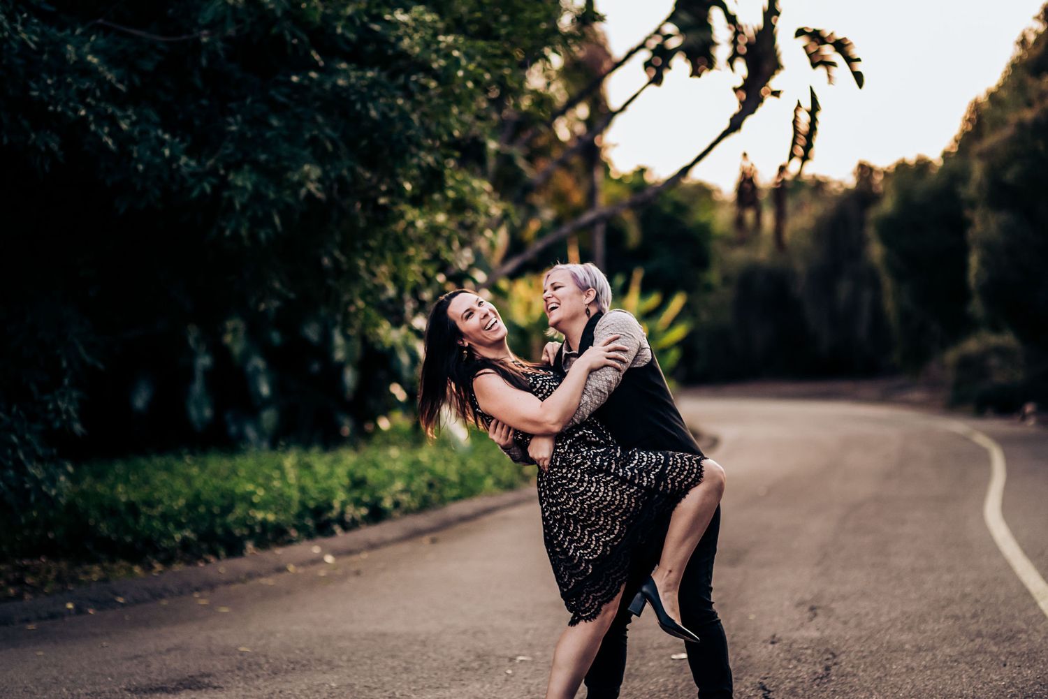 Two people share a playful dance move on a winding garden path.