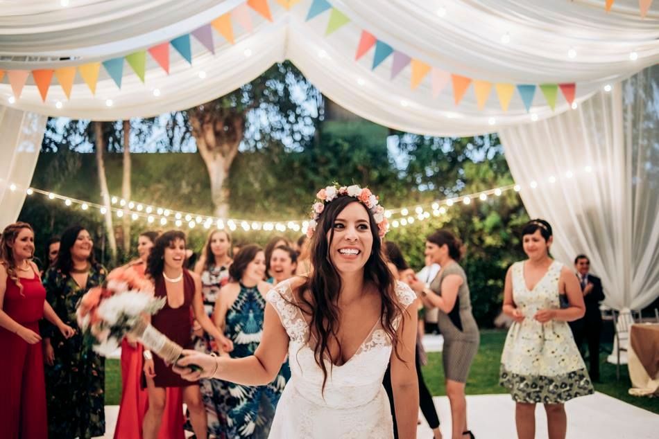Colorful bunting and white drapes decorate an outdoor wedding reception space.