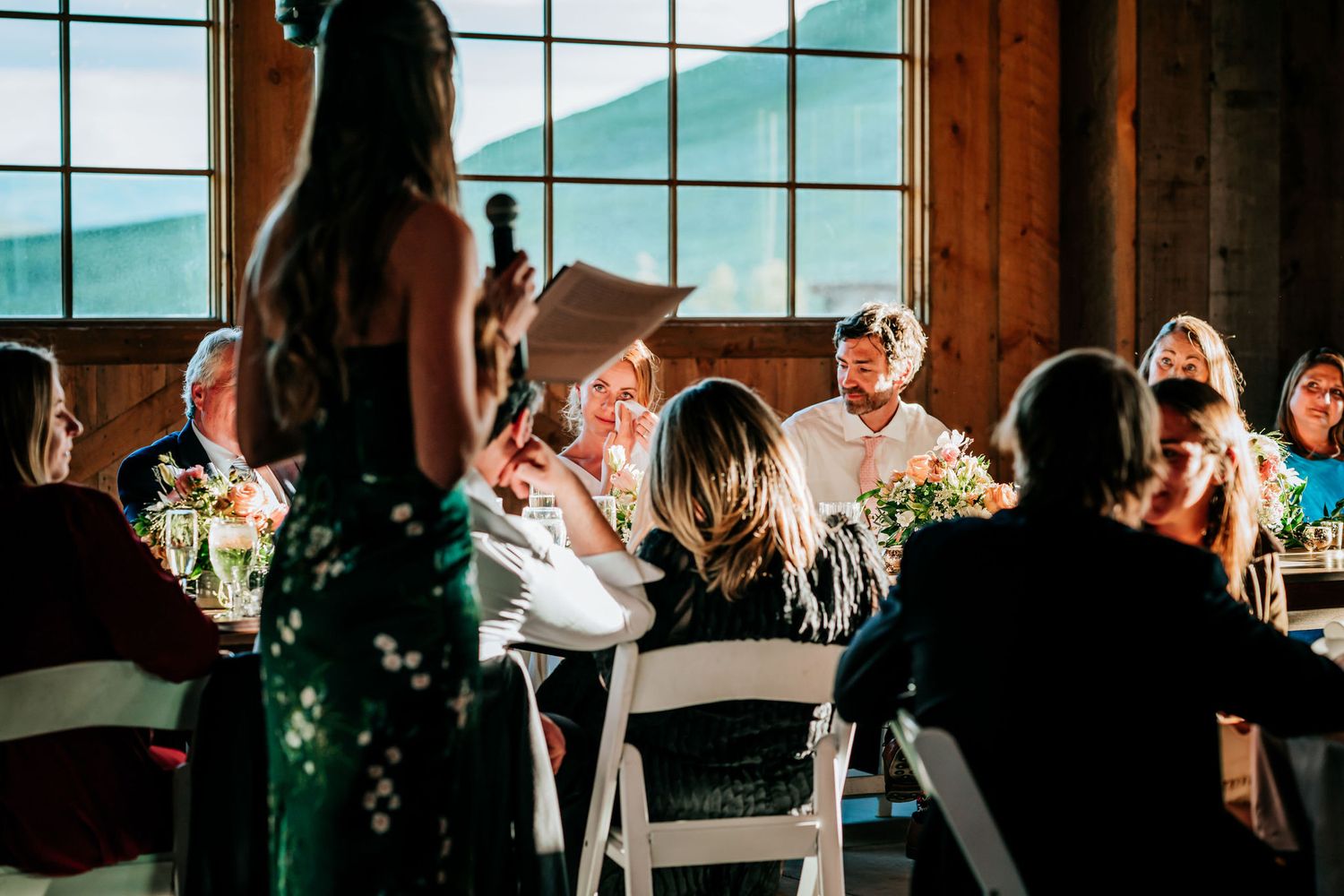 A candid moment during a wedding reception with guests sharing laughter at decorated tables.