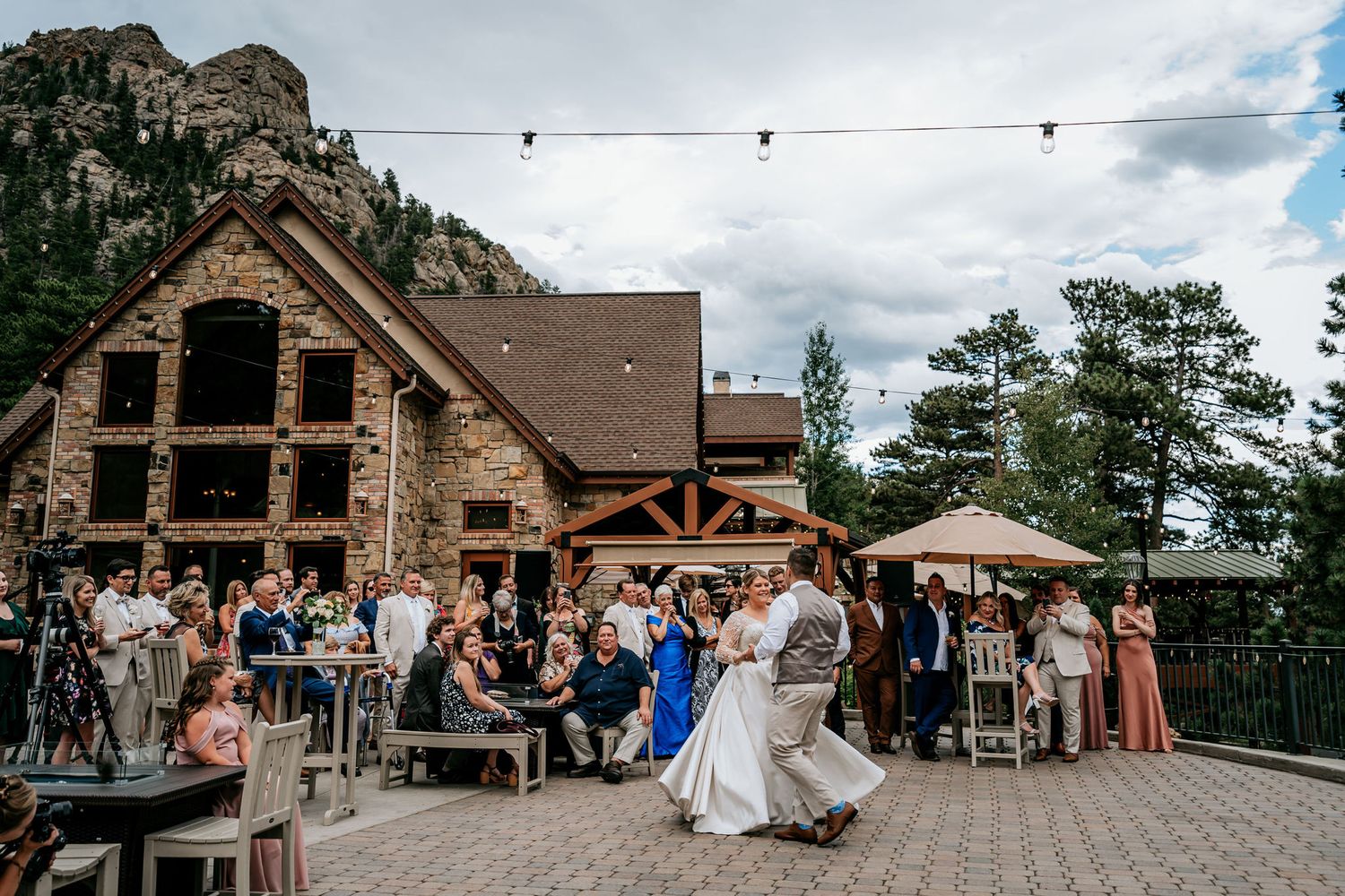 Wedding celebration at rustic mountain venue with stone lodge and outdoor dance floor.