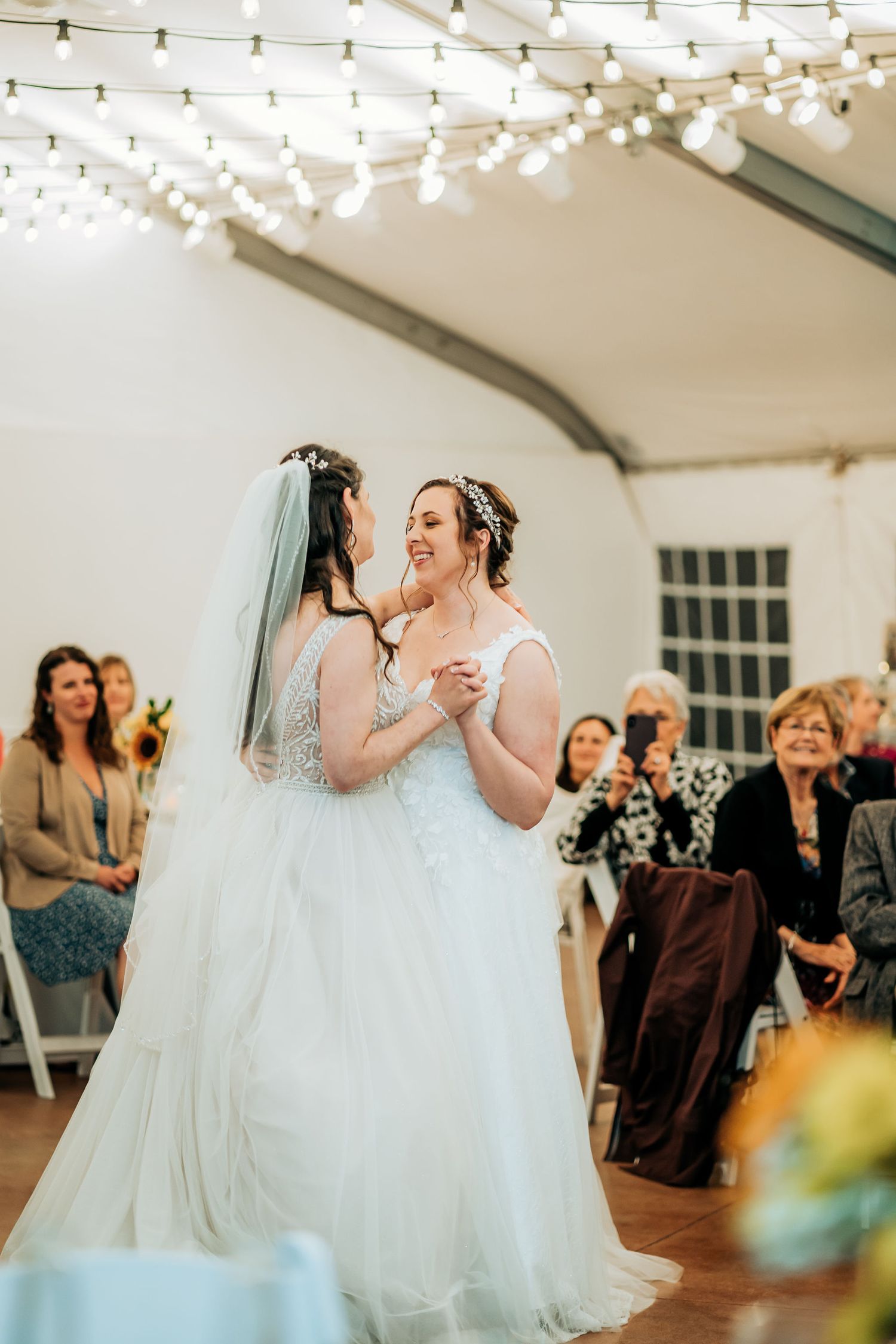 Romantic first dance moment under twinkling string lights at indoor wedding reception.