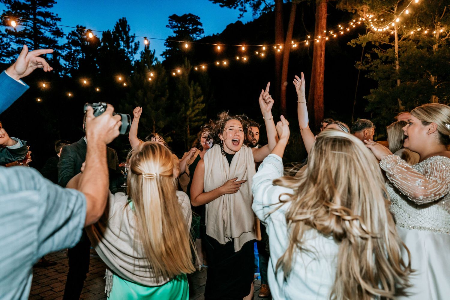 Energetic dancing and celebration at nighttime outdoor wedding reception.