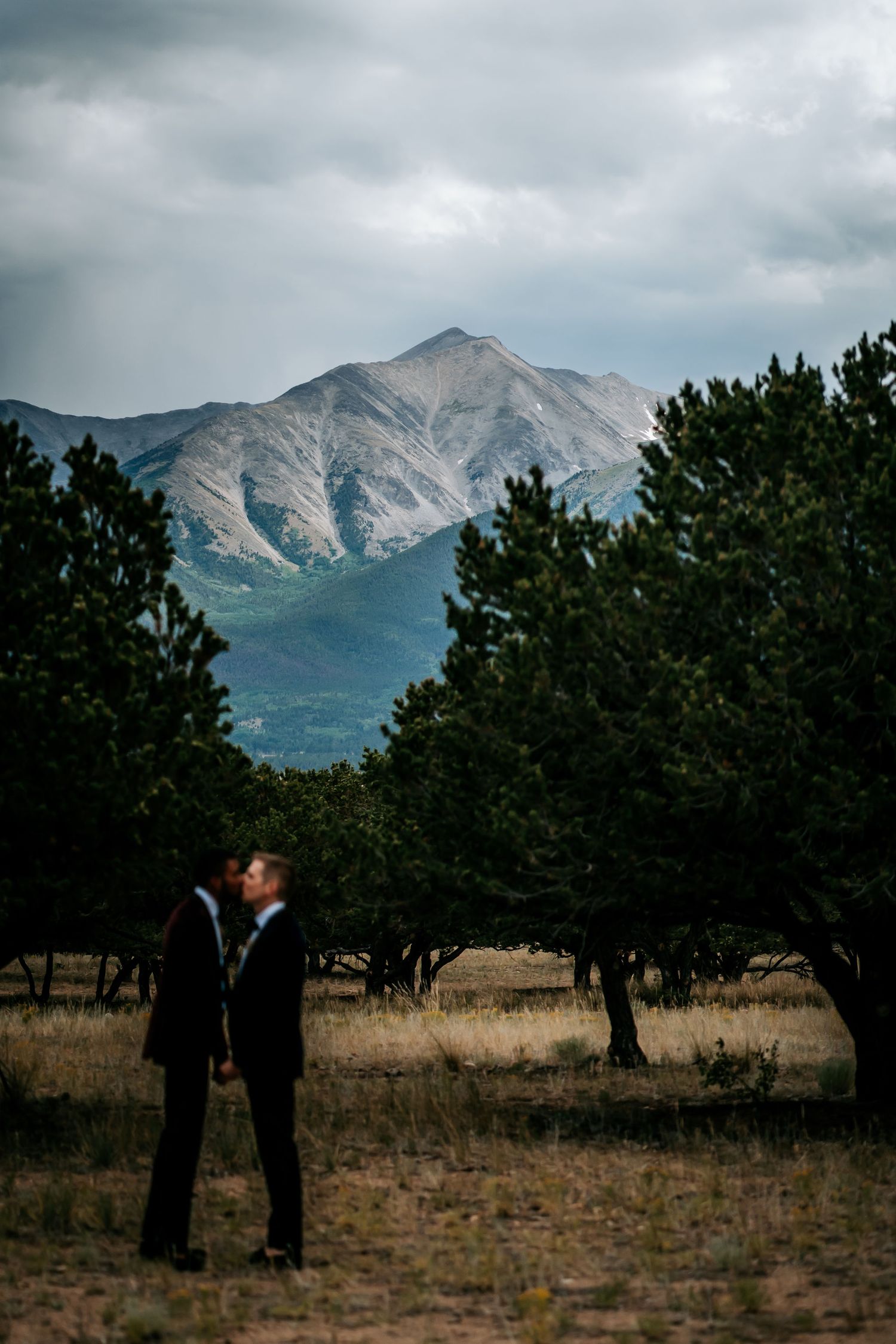 Silhouette of couple sharing intimate moment against dramatic mountain landscape.
