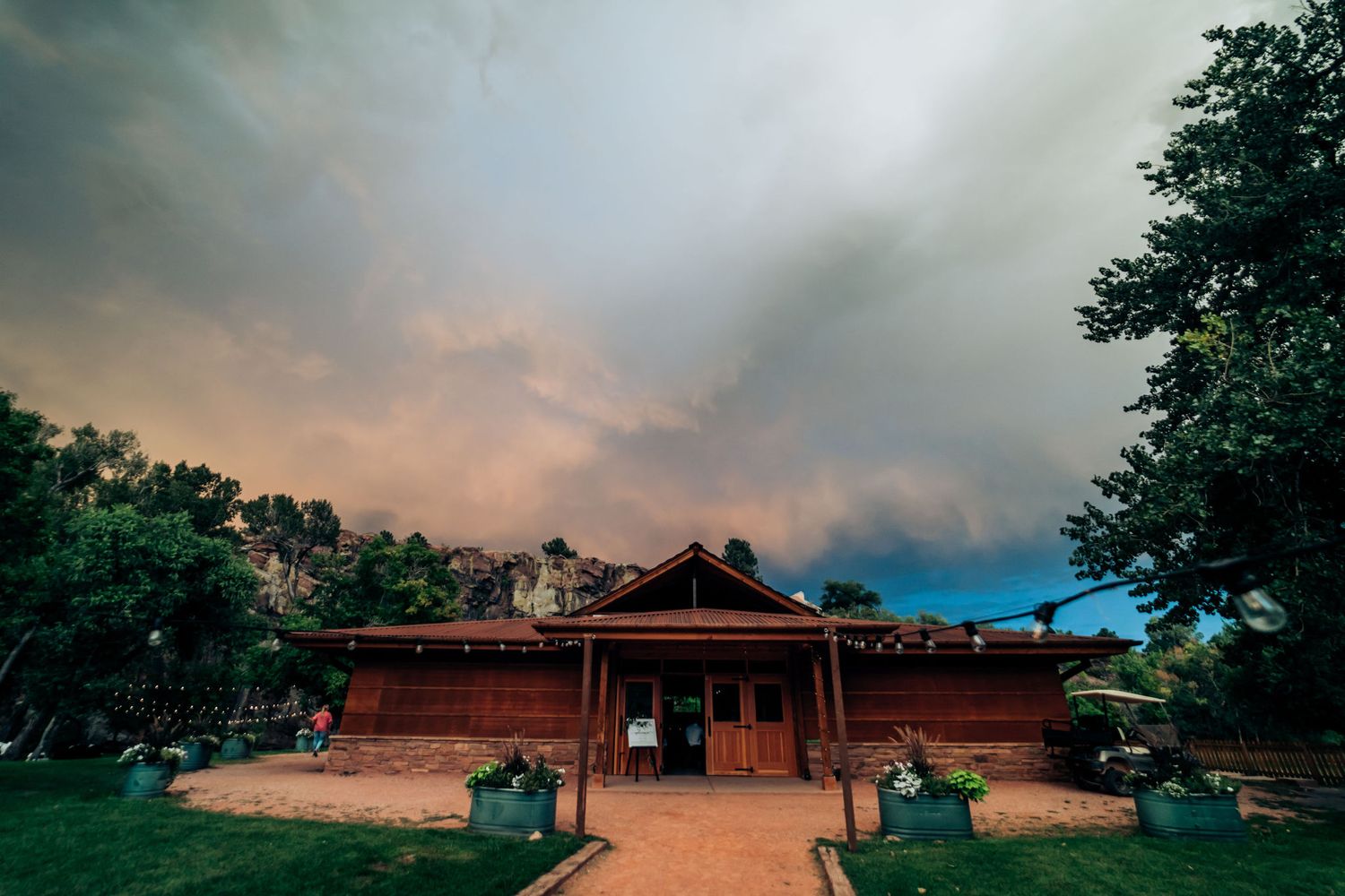 Rustic venue exterior under dramatic stormy sunset sky with glowing clouds.