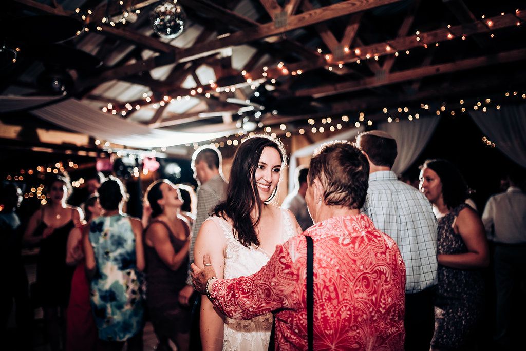 Reception attendees share conversations under warm string lights at an indoor venue.