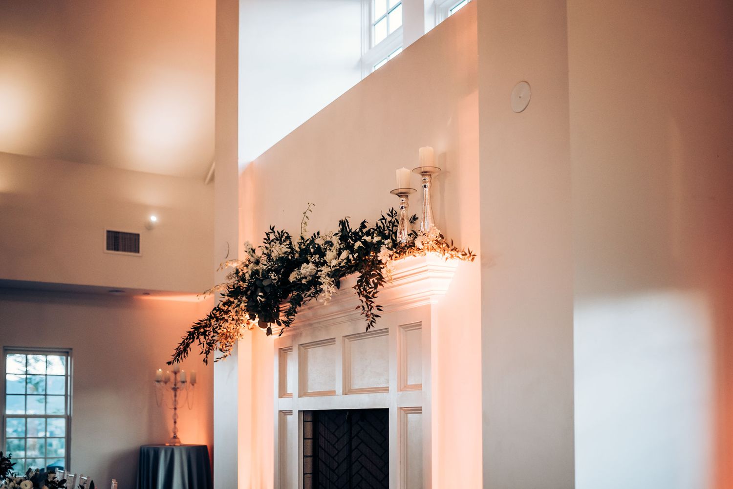 Modern wedding venue interior with floral arch and dramatic lighting.