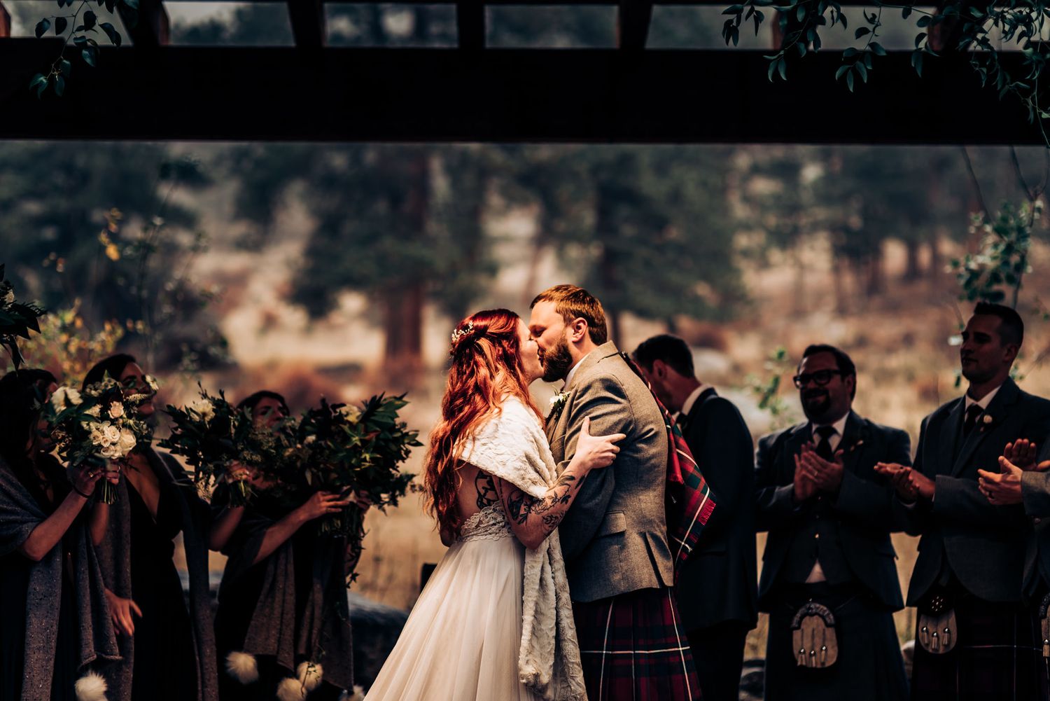 Romantic outdoor wedding ceremony with Scottish elements and bridal party in traditional attire.