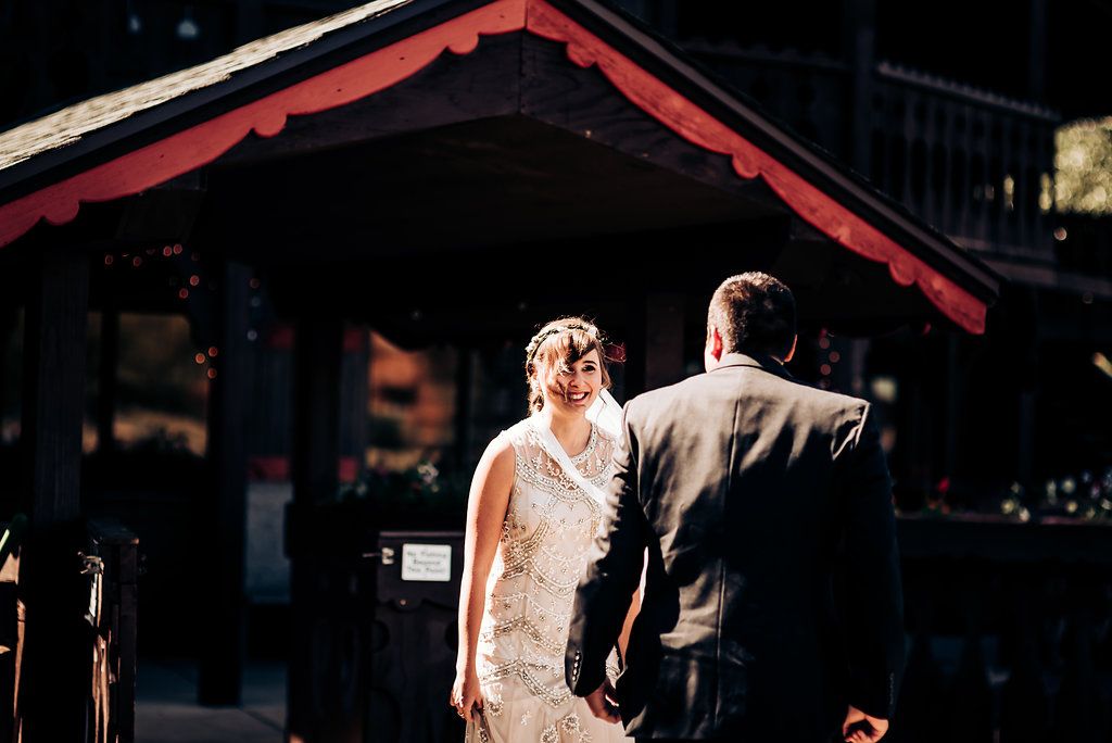 A couple stands in front of a red-trimmed building during their outdoor wedding ceremony.