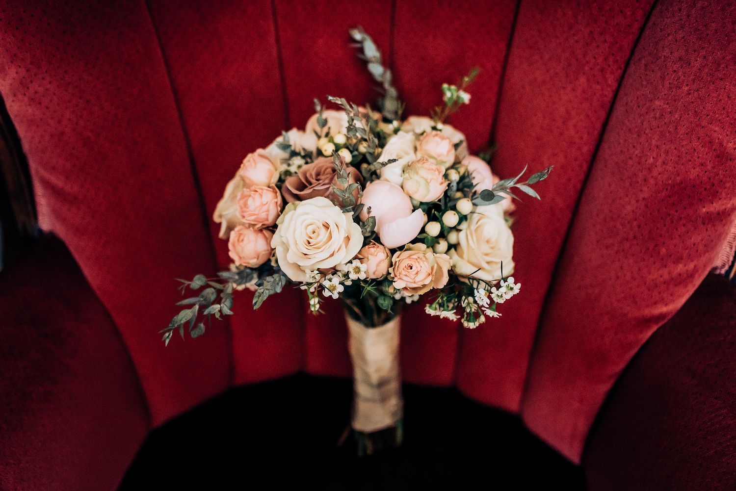 Romantic bridal bouquet with pink and white roses against deep red velvet background.