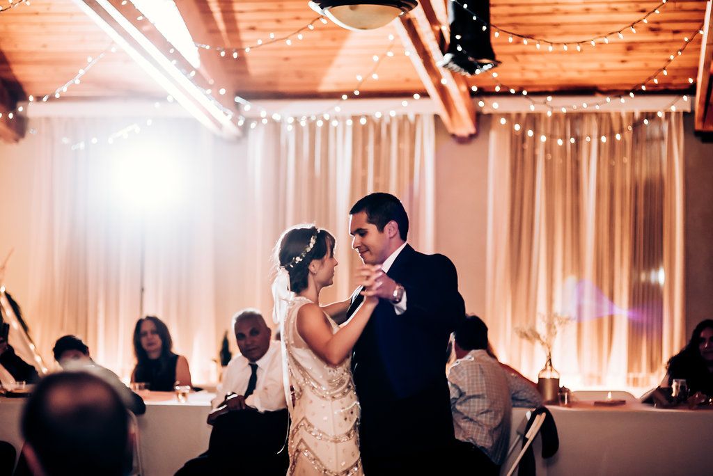 Dancing couple illuminated by warm lighting at evening wedding reception.