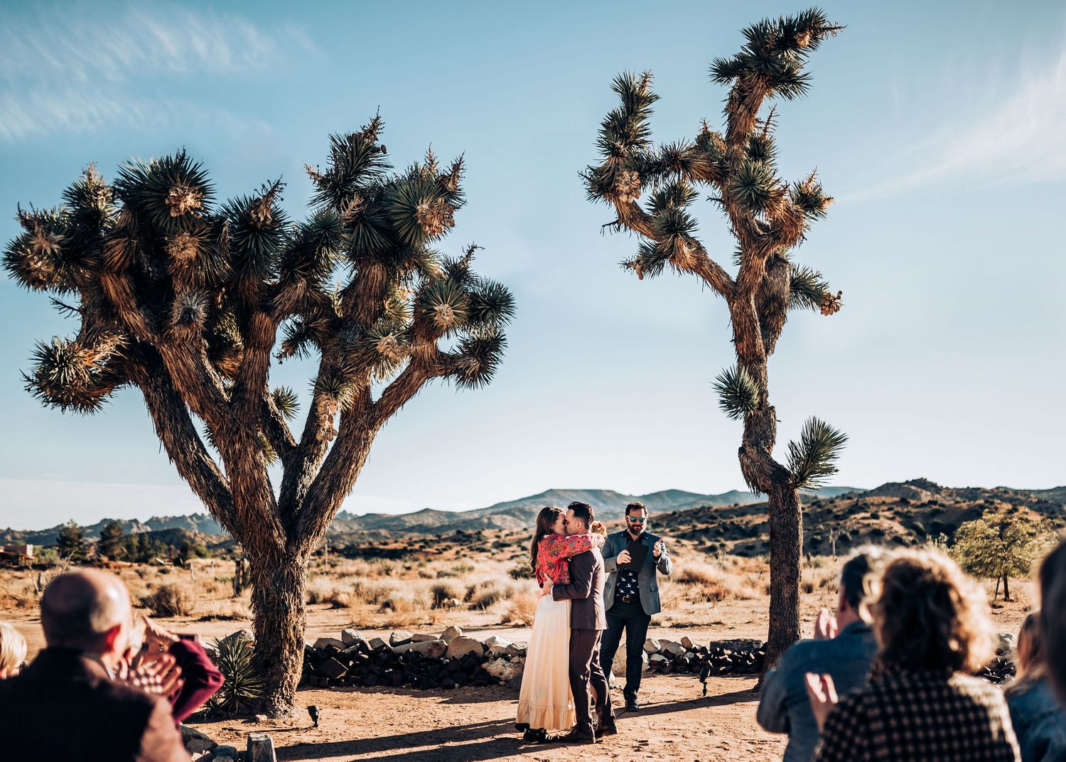 An outdoor wedding ceremony takes place in a desert landscape with iconic Joshua Trees.