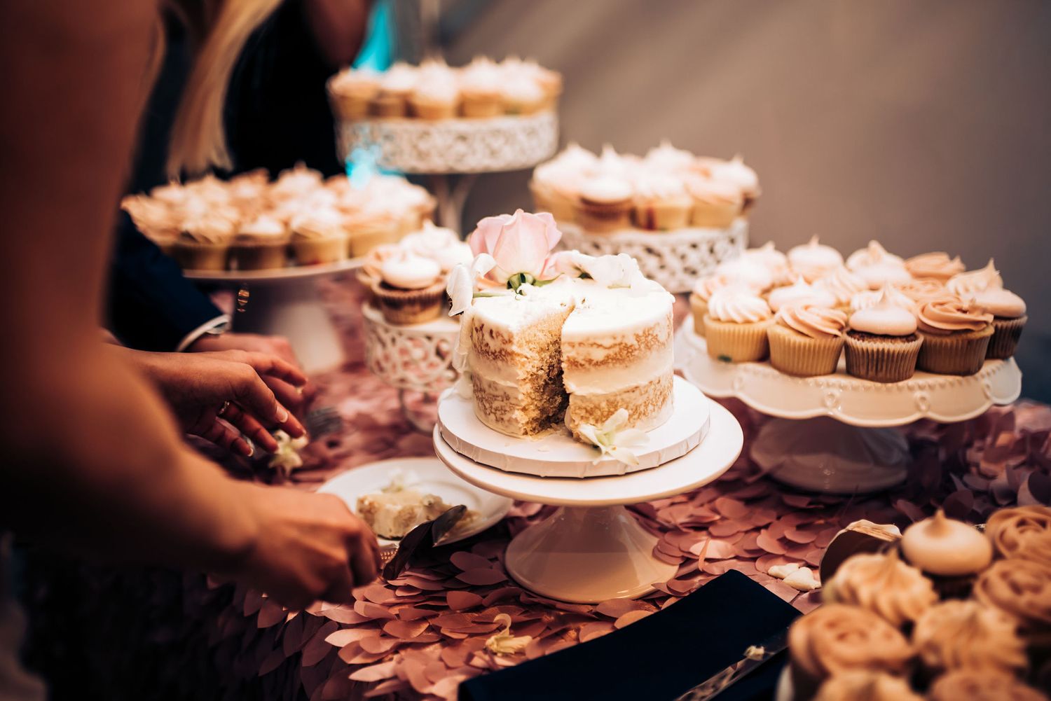 Wedding cake display featuring multiple tiers of cupcakes arranged on elegant white stands.