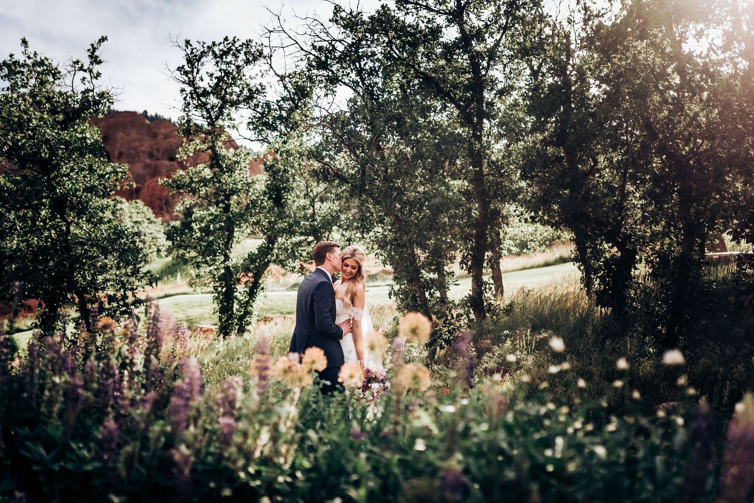 Artistic wedding photo of couple surrounded by nature and mountain scenery.