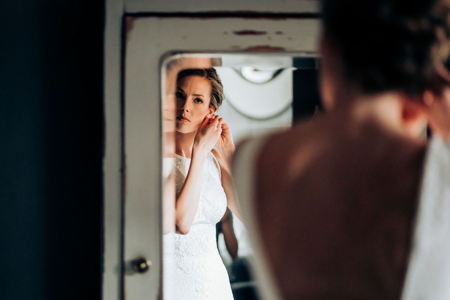 Wedding dress reflection captured in a vintage mirror during bridal preparations.