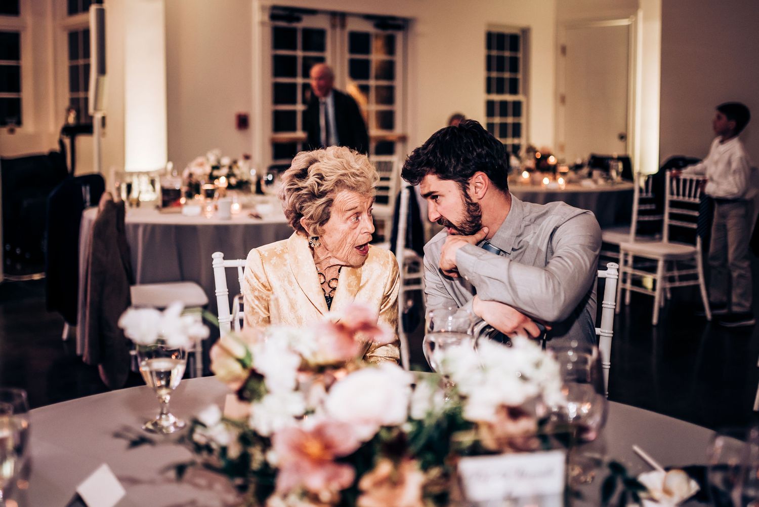 Guests share an intimate moment at an elegant wedding reception table decorated with floral centerpieces.