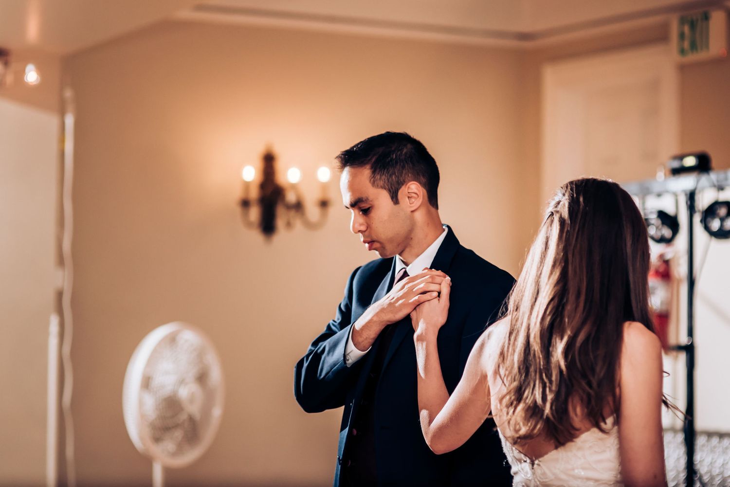 A couple shares an intimate dance moment in an elegantly lit ballroom.