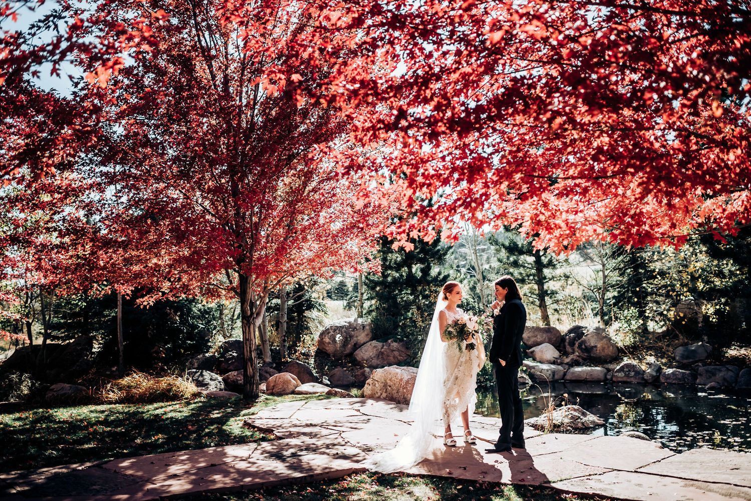 Wedding ceremony captured under brilliant red maple trees on a stone patio.