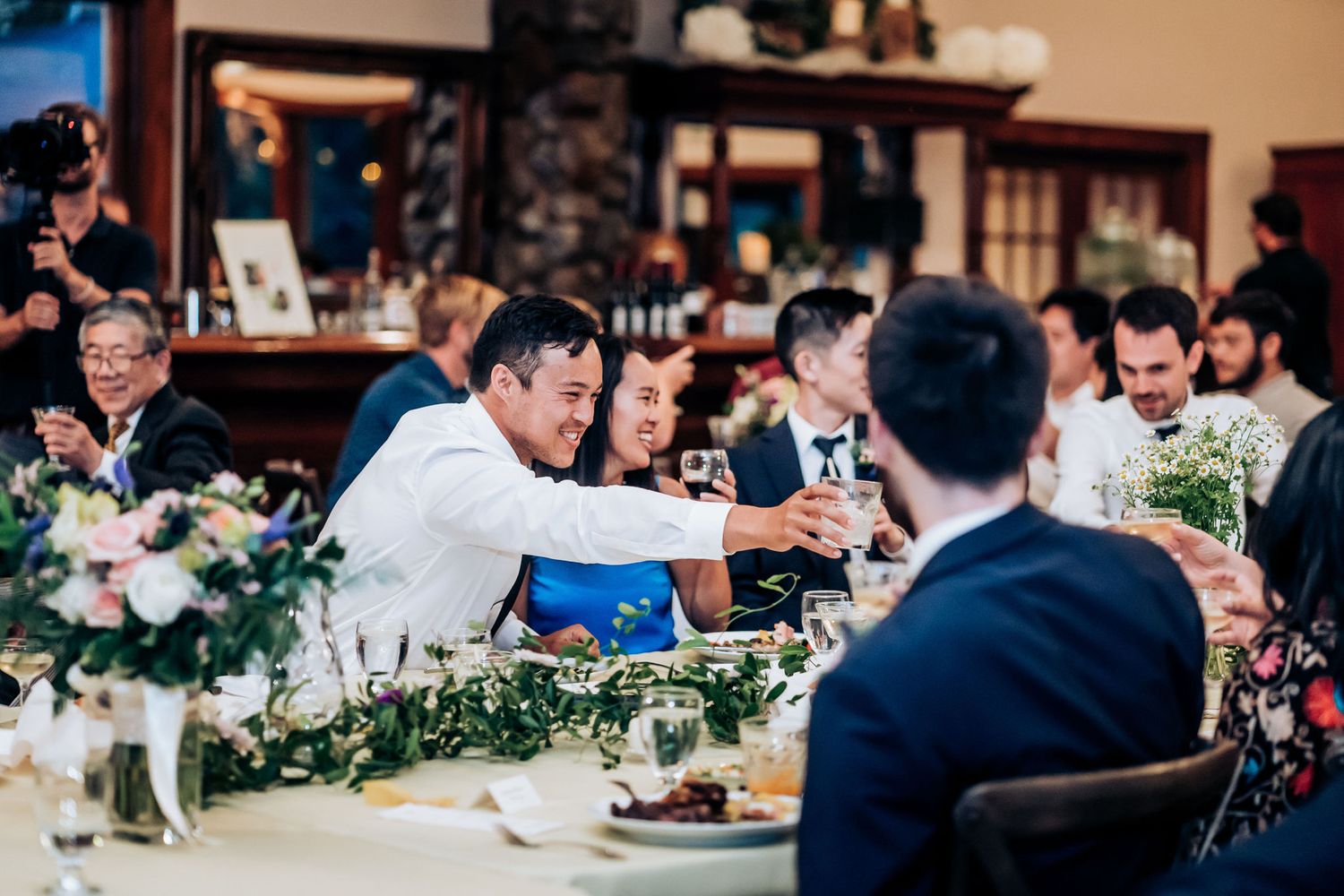 Wedding reception dinner with elegant table decorations and greenery garland centerpieces.