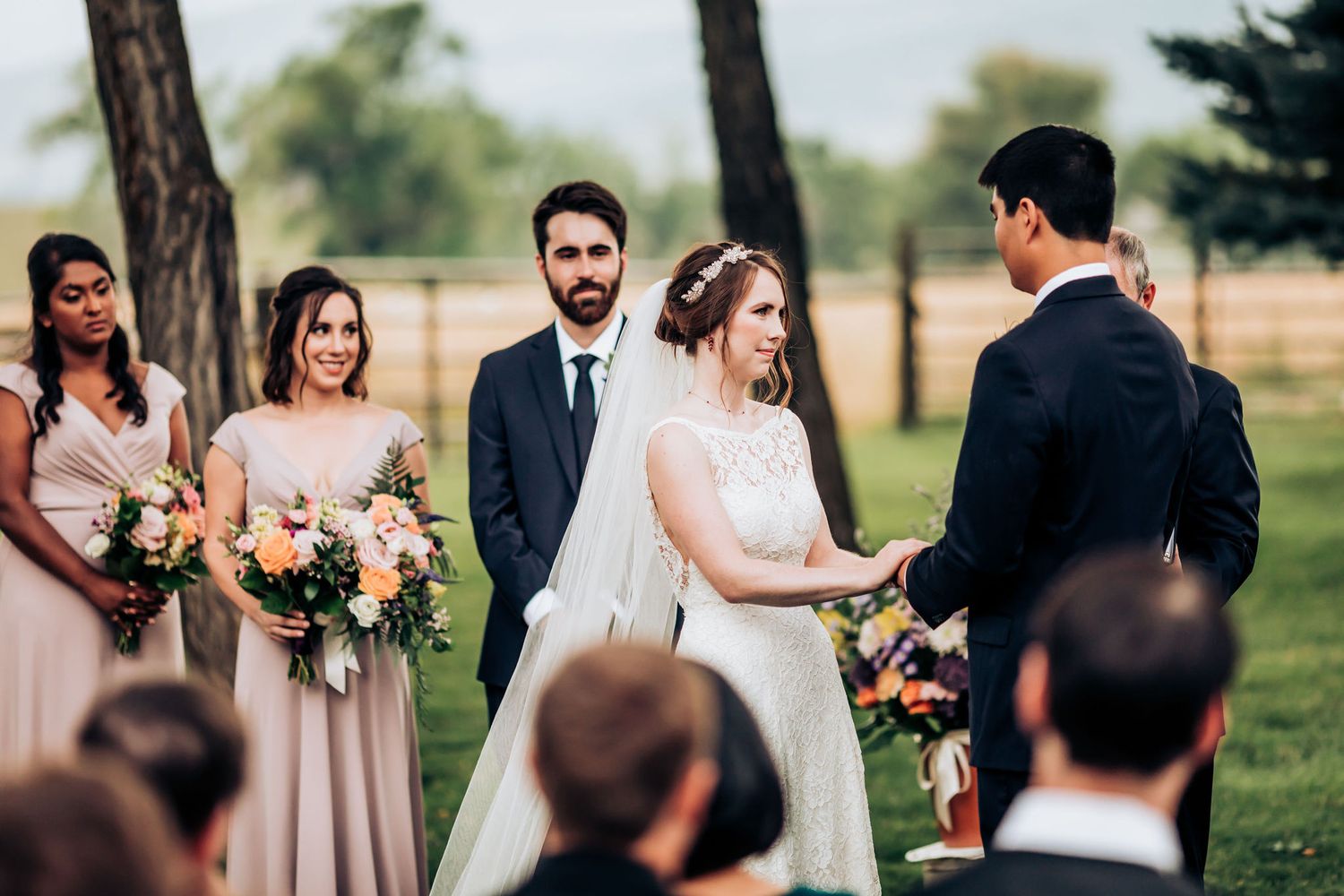 An intimate outdoor wedding ceremony surrounded by tall pine trees and guests in formal attire.
