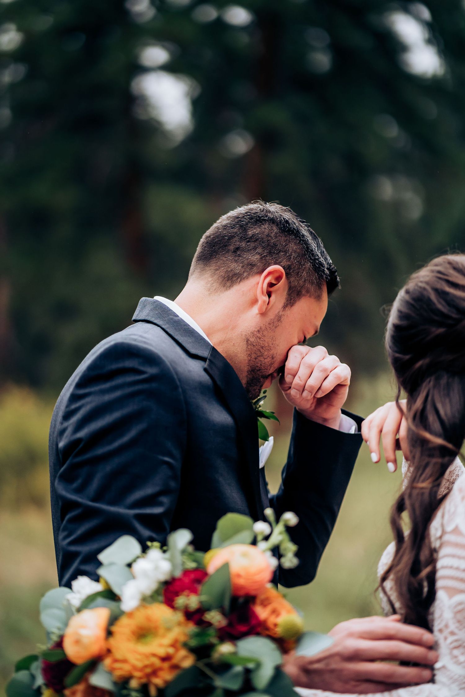 Emotional wedding moment with autumn floral bouquet in outdoor setting.