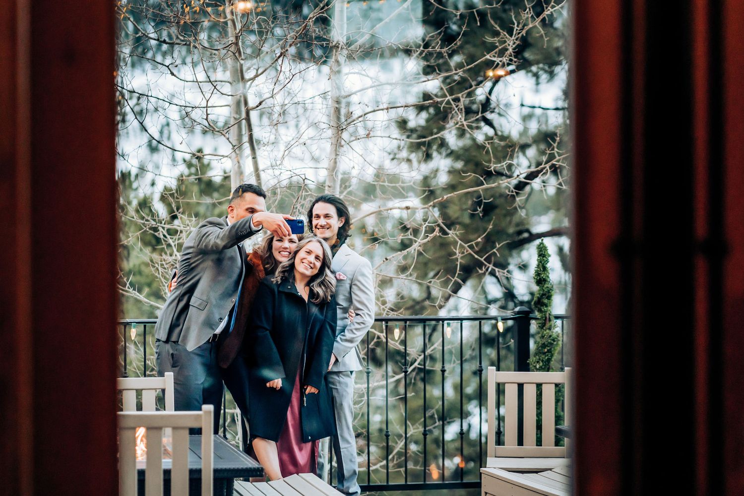 Wedding guests sharing a candid moment on a balcony with snowy scenery behind them.