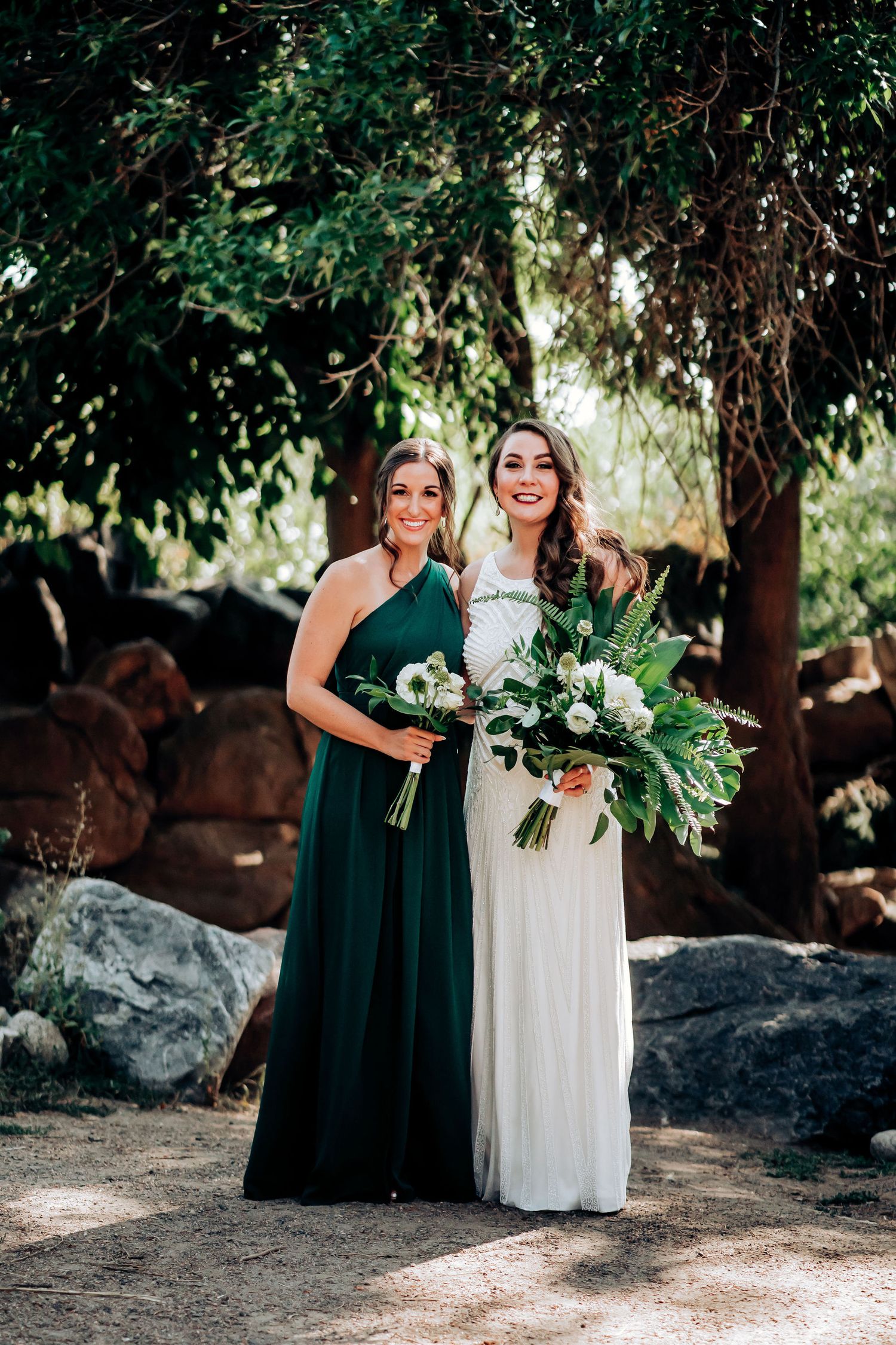 Wedding party members pose with elegant bouquets featuring monstera leaves in a natural outdoor setting.