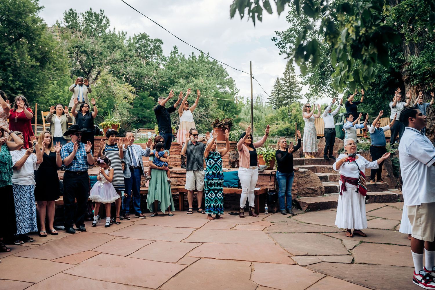 Large group of wedding guests gathering on an outdoor stone patio during celebration.